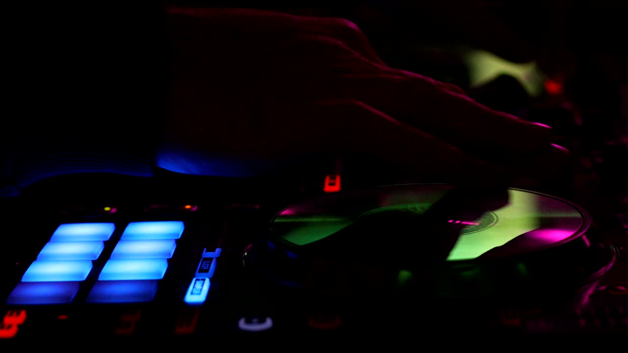 cerca de las manos de un dj tocando en un controlador digital en un club nocturno oscuro