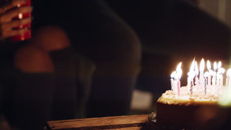 group of friends celebrating birthday party on rooftop at night beautiful young woman blowing candles enjoying friendship having fun sharing celebration