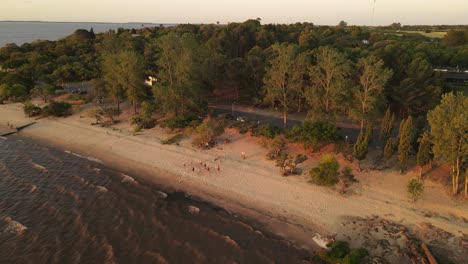 Toma-Aérea-De-Personas-Jugando-Voleibol-De-Playa-En-La-Costa-De-Fray-Bentos,-Uruguay