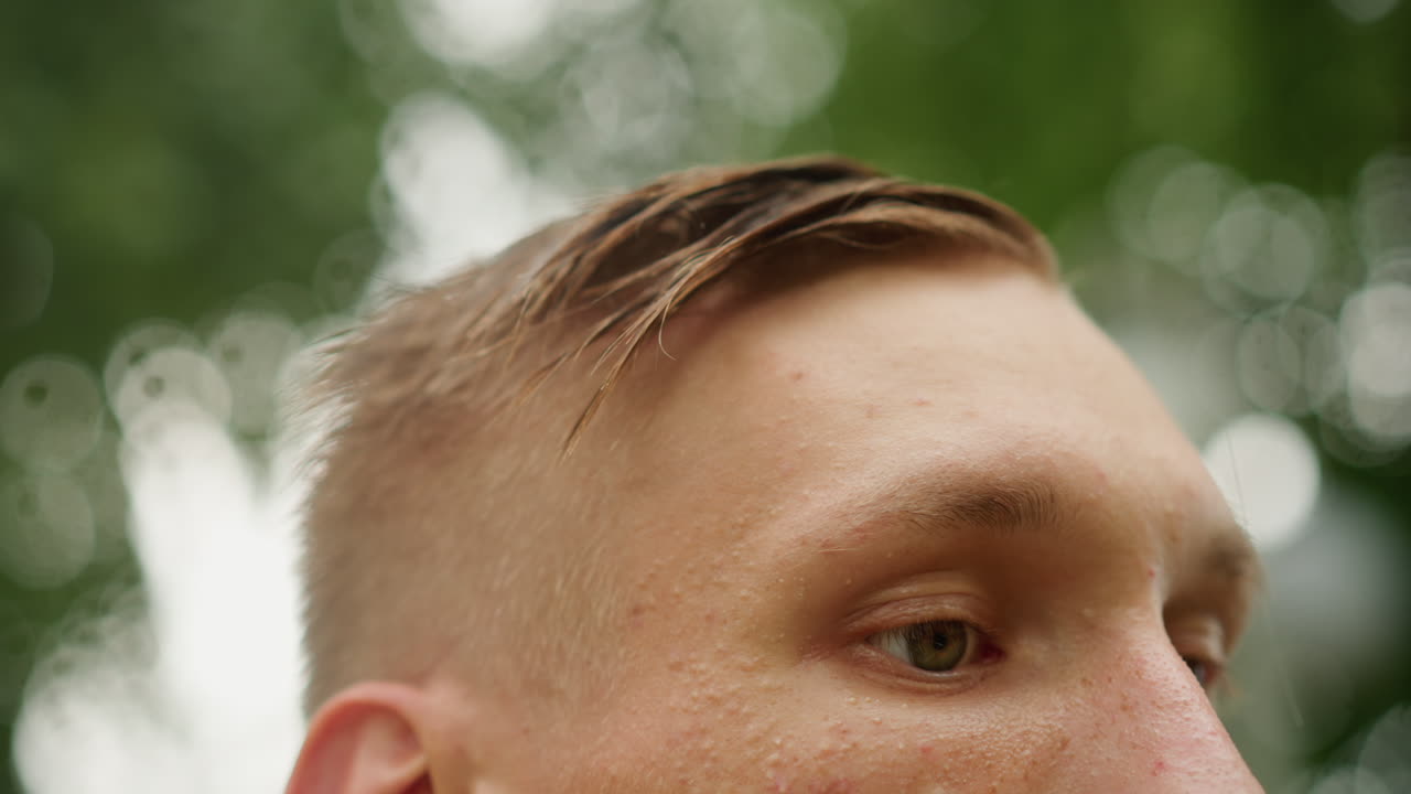 초조한 후보자가 젖은 머리를 정리하는 모습, 남자가 젖은 앞머리를 손가락으로 매만지는 클로즈업, 이마에 옅은 땀, 흐릿한 나무 배경, 긴장했지만 집중된 표정, 적합한 영상