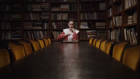 mujer concentrándose en el ajedrez en una biblioteca