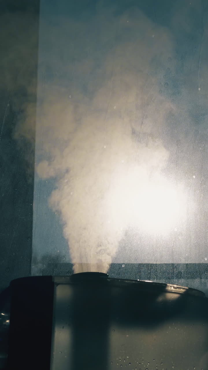 CU shot: modern air ionizer emits dense steam to humidify air and neutralize bacteria near window in room extreme close view