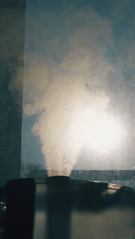 cu shot: modern air ionizer emits dense steam to humidify air and neutralize bacteria near window in room extreme close view