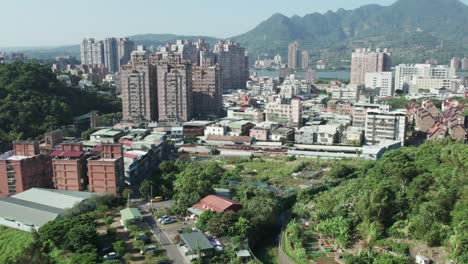 Drohne-Fliegt-über-Gebäude-Und-Parks-In-Zhuwei,-Bezirk-Tamsui,-Taipeh