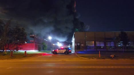 el coche de la policía establece el perímetro en un incendio industrial, de noche.