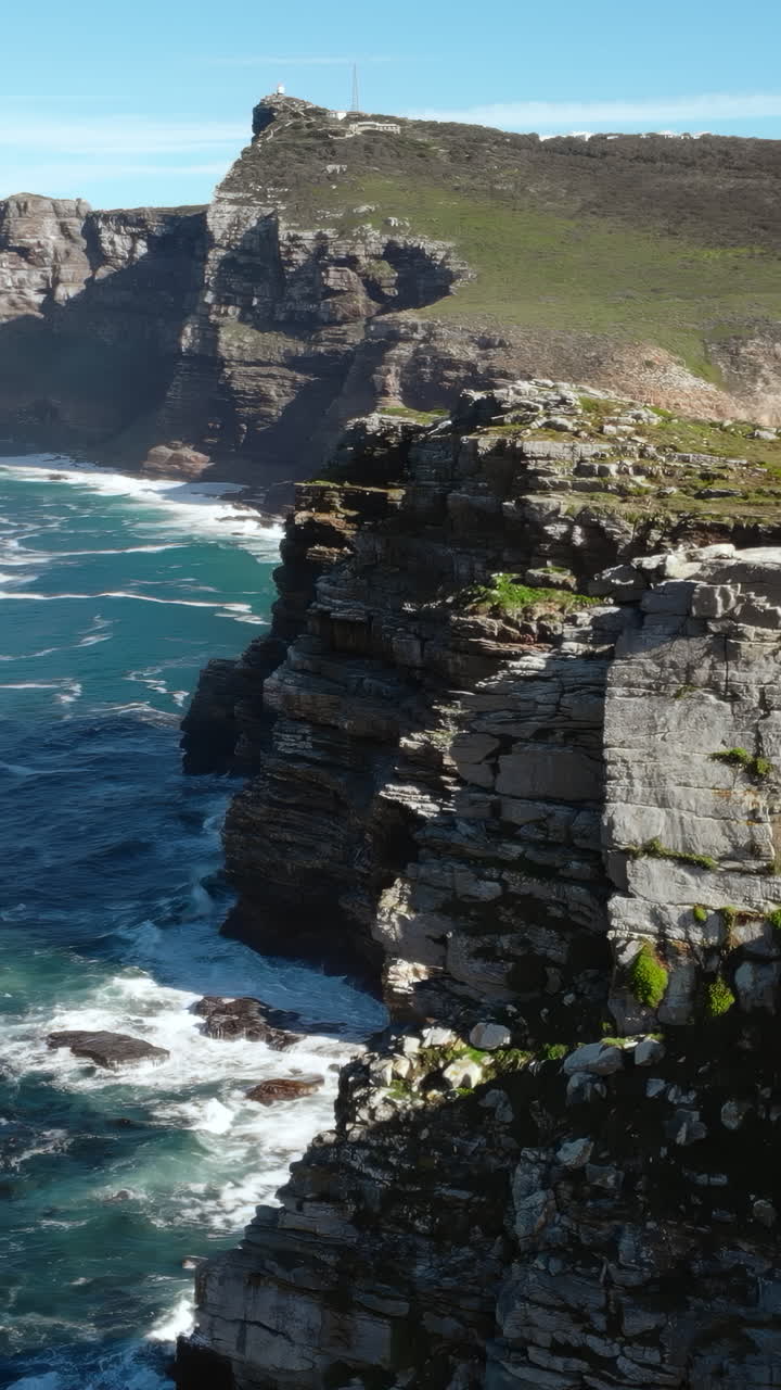 Powerful Ocean Waves Crashing Against Rugged Cliffs with Lighthouse
