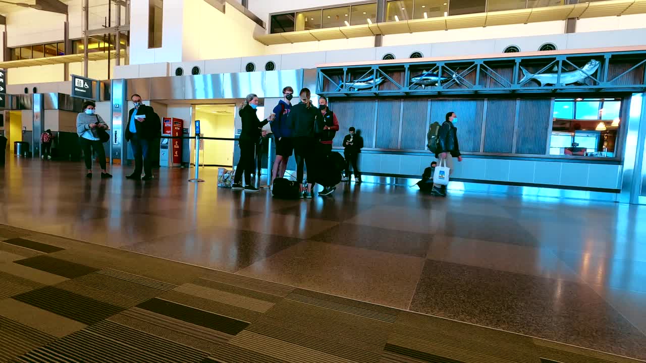 Passengers standing in airport casually dressed wearing mask waiting on flight
