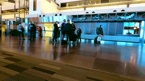 passengers standing in airport casually dressed wearing mask waiting on flight