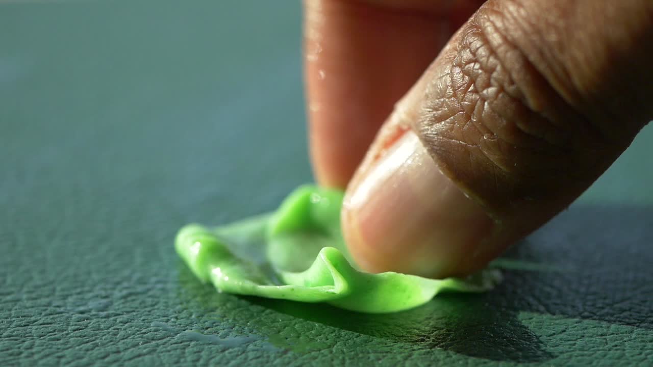 Person pushing green gum on a surface
