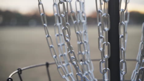 el disco de golf de disco de núcleo interno azul golpea las cadenas de la canasta de golf de disco y luego son recogidos por la mano del golfista de disco