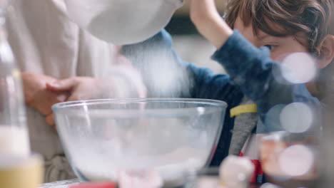 little boy helping mother bake in kitchen mixing ingredients sifting flour using sieve preparing recipe for cupcakes at home