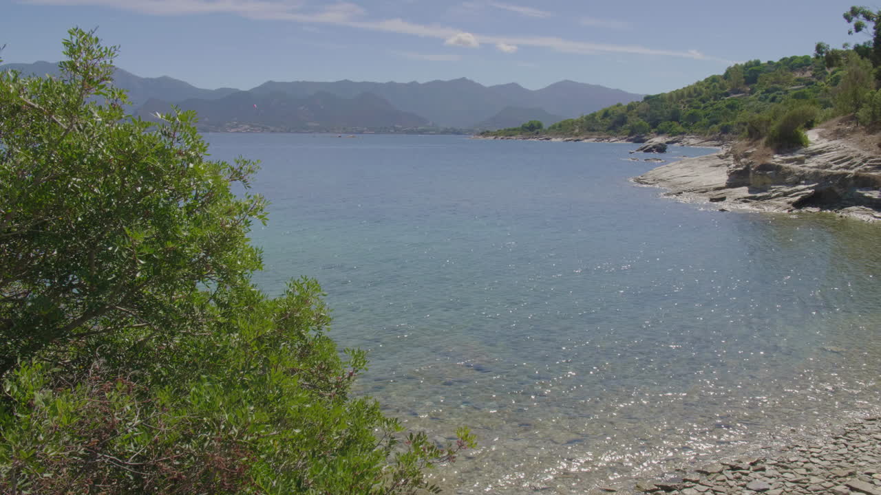 Saint-Florent Corsica coast rocky shorelines under a bright blue sky sunny view of crystal clear turquoise waters serene Mediterranean landscape untouched natural beauty northern Corsican seaside