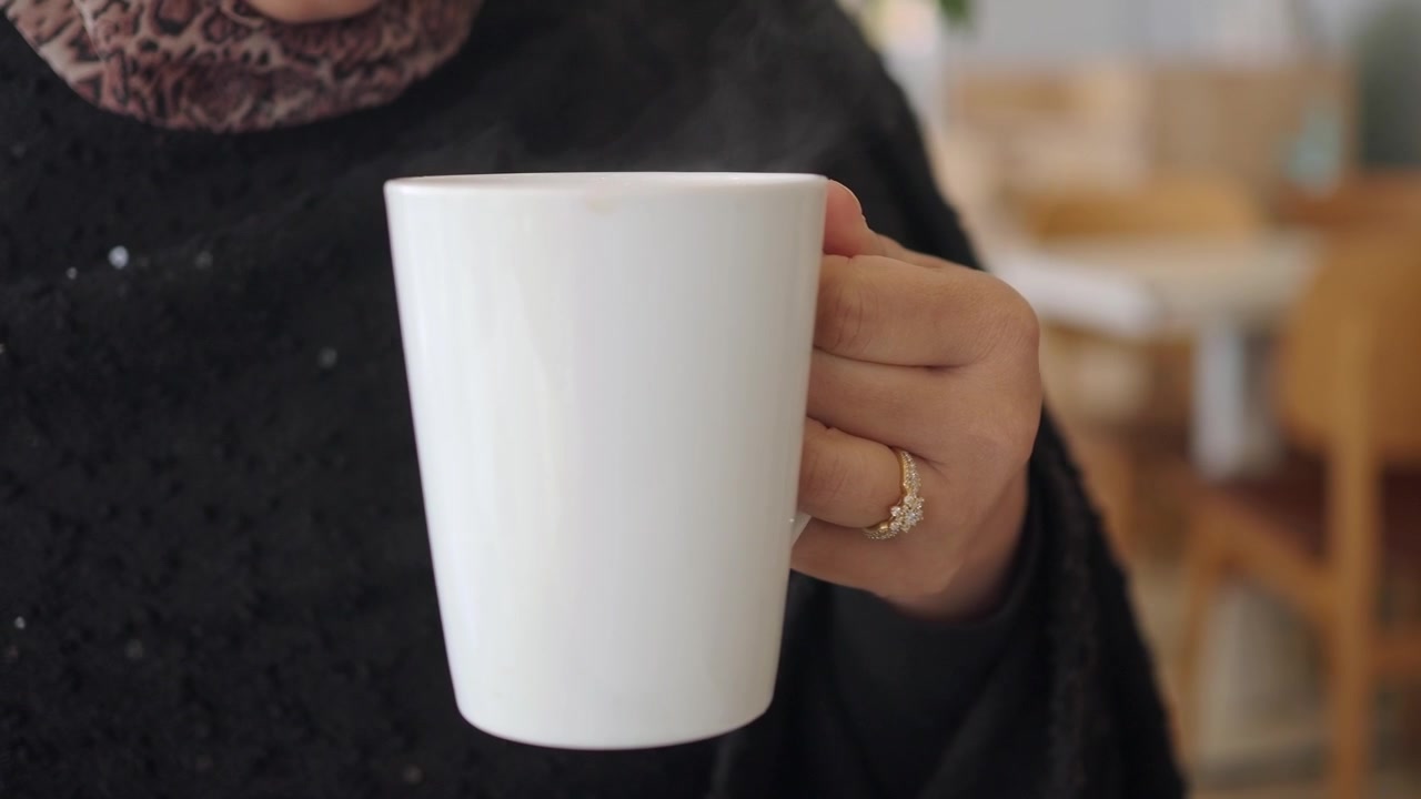 Kvinde med hijab drikker varm te fra et hvidt krus