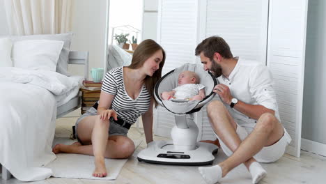 close - up of happy parents watching their little baby sleep in a rocking chair for babies at home in a white apartment