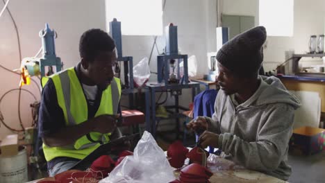 colleagues discussing about the cricket ball in factory