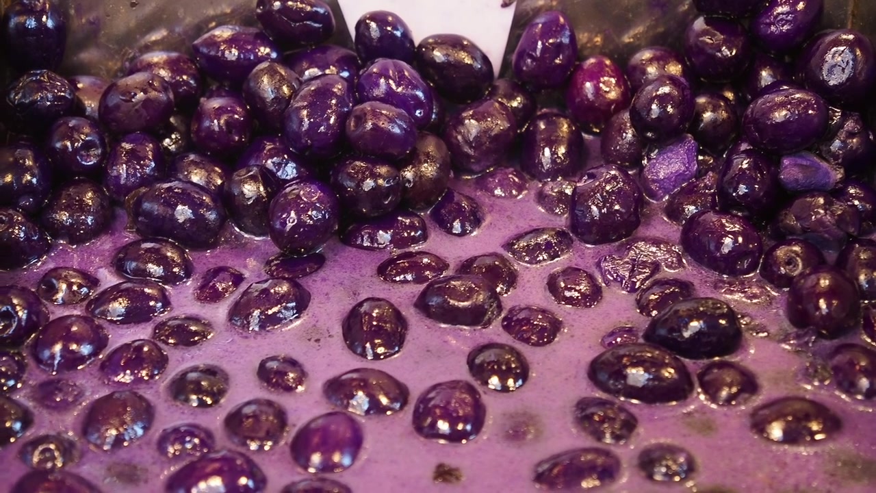Primo piano di olive viola lucide in una salamoia viola chiaro