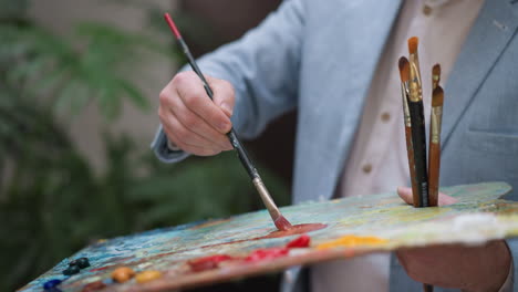 painter mixes pigments on slab closeup. inspired designer works with color palette at session in workshop. professional painter enjoys drawing in studio