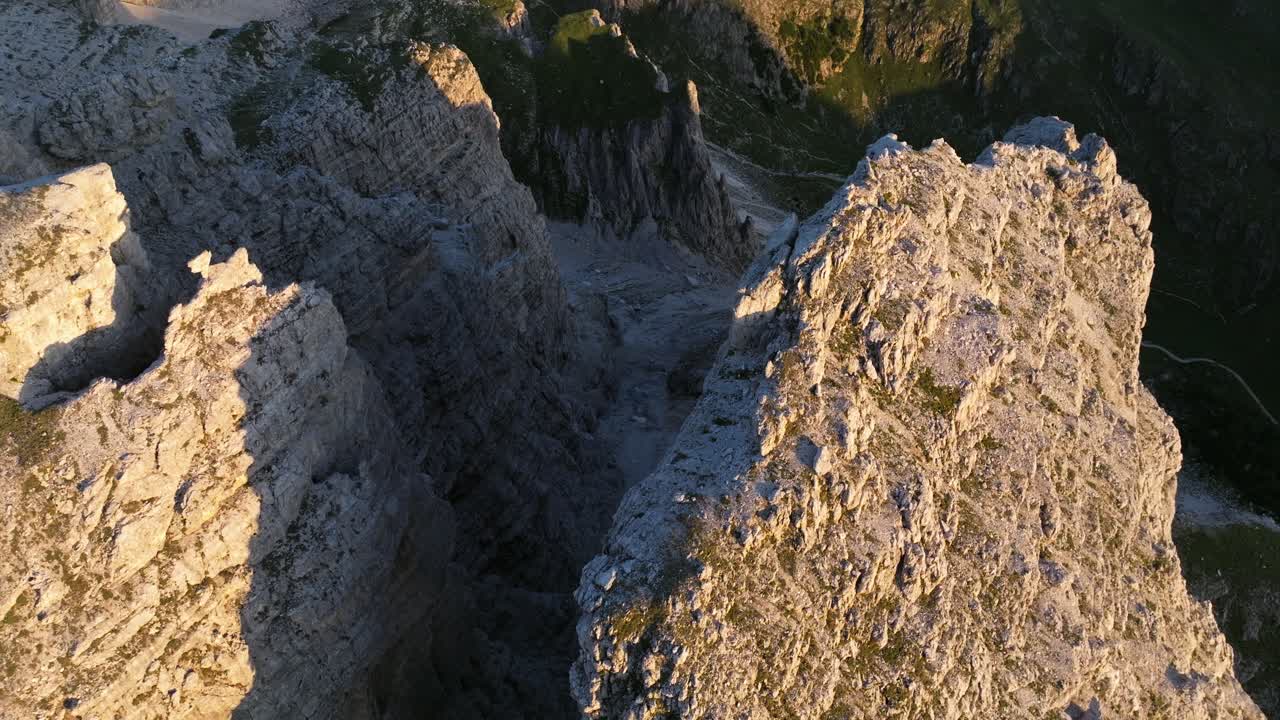 A bird's-eye view of the pristine Alpine meadows of the Dolomites, glistening under the morning sun, with misty valleys below