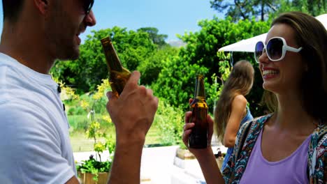 couple interacting while having a bottle of beer near poolside