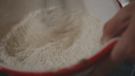 pastry chef whisking flour on bowl for dough in the kitchen