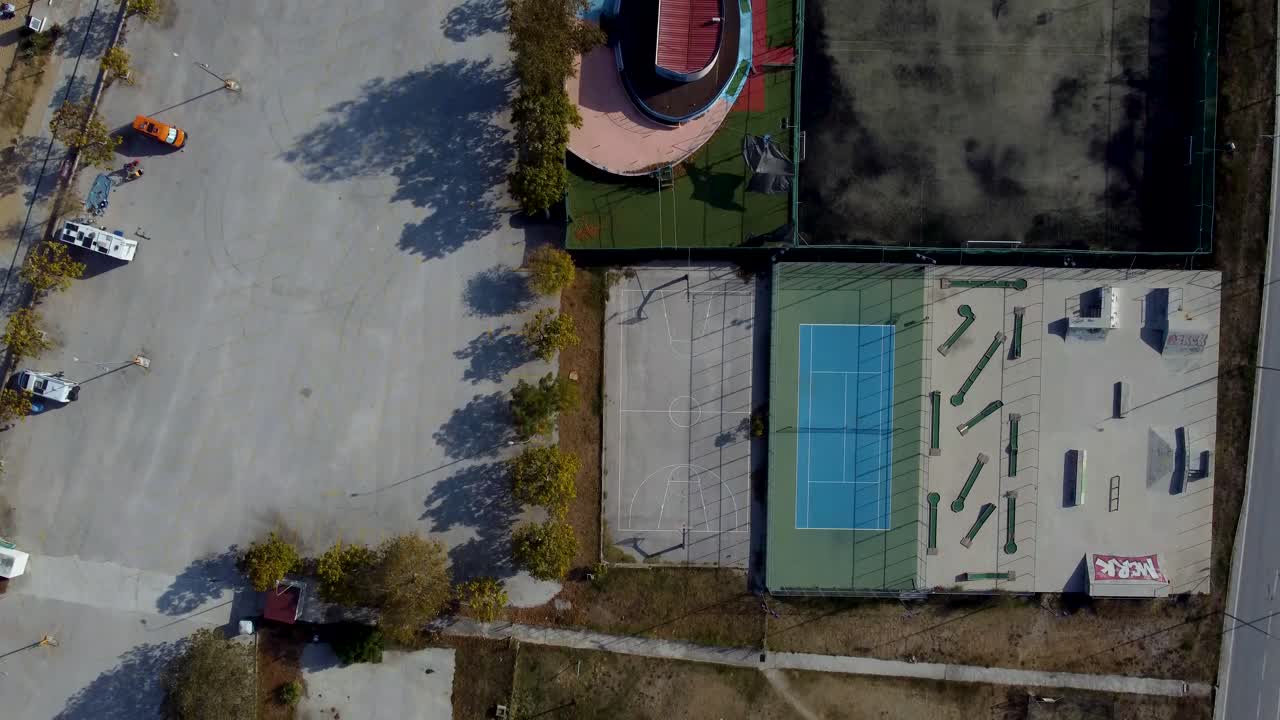 Aerial top down pan over outdoor sports facilities with tennis, basketball, mini golf and skate park