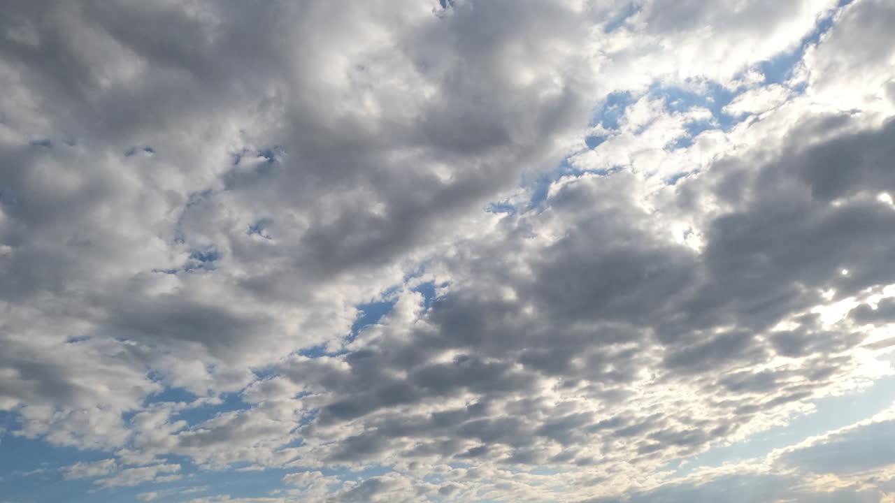 Grey clouds flow slowly by the skies. Rainy cloudscape forming in the atmosphere but then blue sky appears. Timelapse.