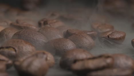 Close-up-macro-shot-of-roasting-coffee-beans-in-a-hot-oven,-thick-smoke-coming-from-the-beans-as-they-crack-and-brown-to-give-the-barista-the-perfect-desired-flavour