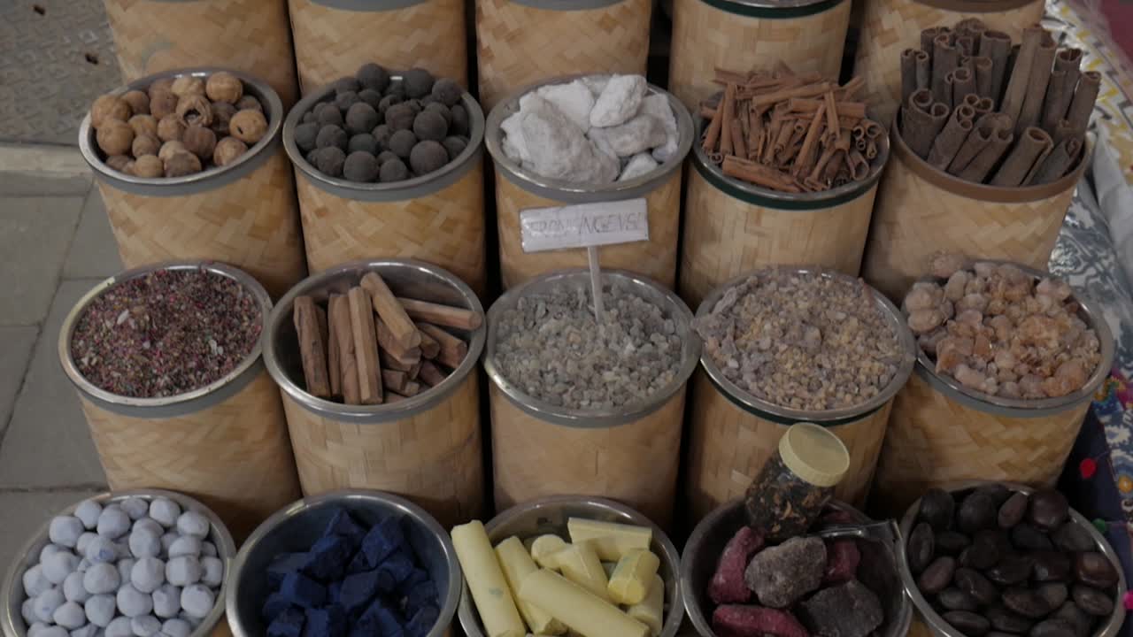 Many spices for sale at a local shop, each in its own container. Tilting shot.