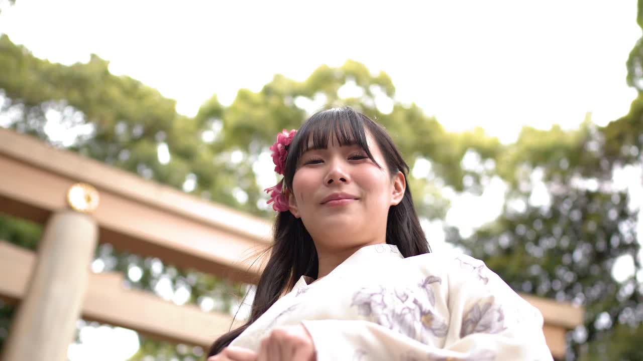 神社で着物を着て笑顔を見せる日本人女性のローアングルショット。