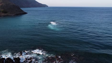 Rocky-Island-in-blue-sea-on-Crete-coastline,-aerial-view