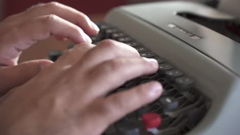 man typing on mechanical desktop typewriter