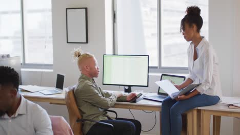 Diverse-business-people-discussing-with-computer-in-creative-office