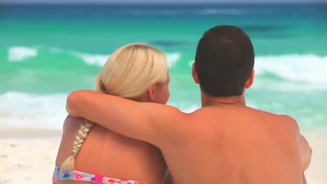 sweet couple sitting hugging on a beach