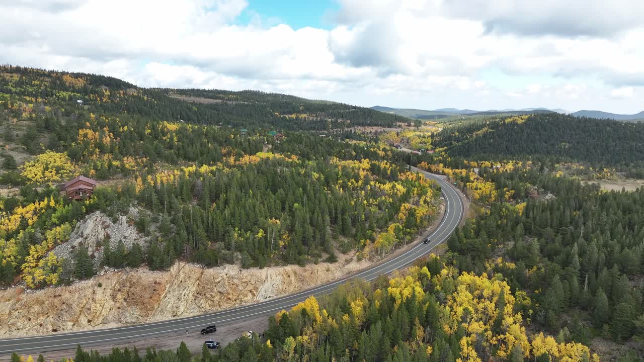 Colorado mountain road during fall aspens. Mountain ranch homes are scattered along the mountainside