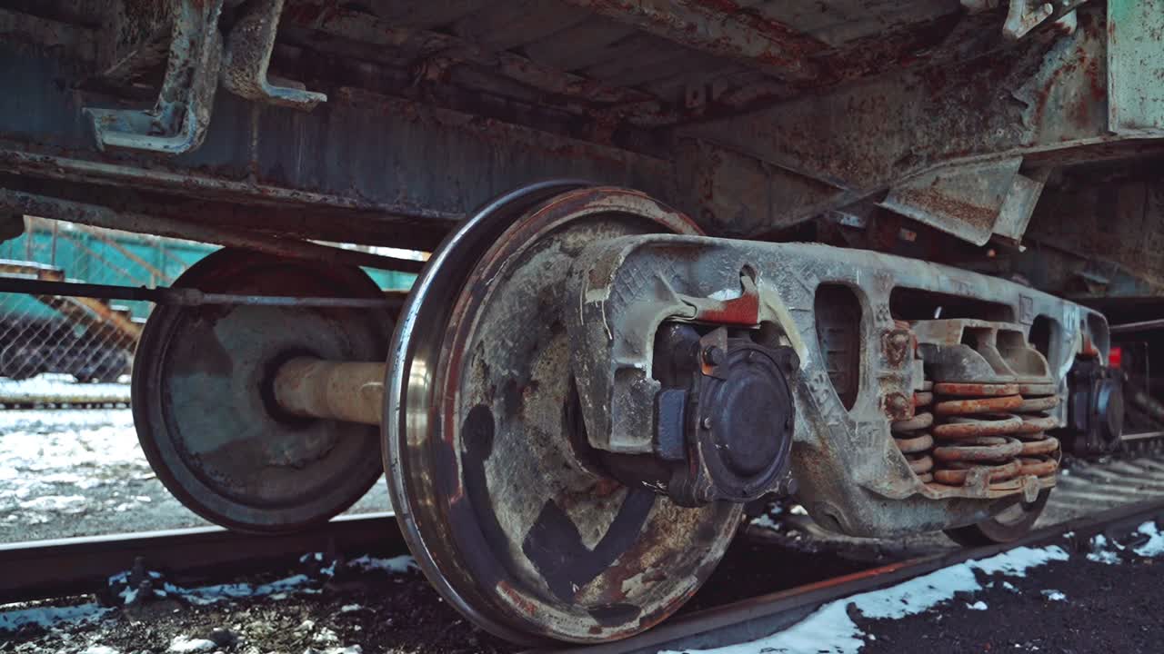 View of the rusty bottom of the container, which moves along the rails on the railway in the winter. Close-up