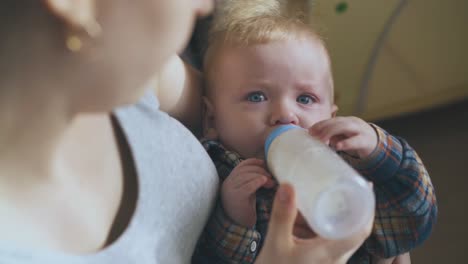 happy mommy rocks son eating milk mix in spacious room