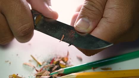 Footage-of-hands-slowly-sharpening-a-pencil-and-some-coloured-pencils-with-a-sharp-knife