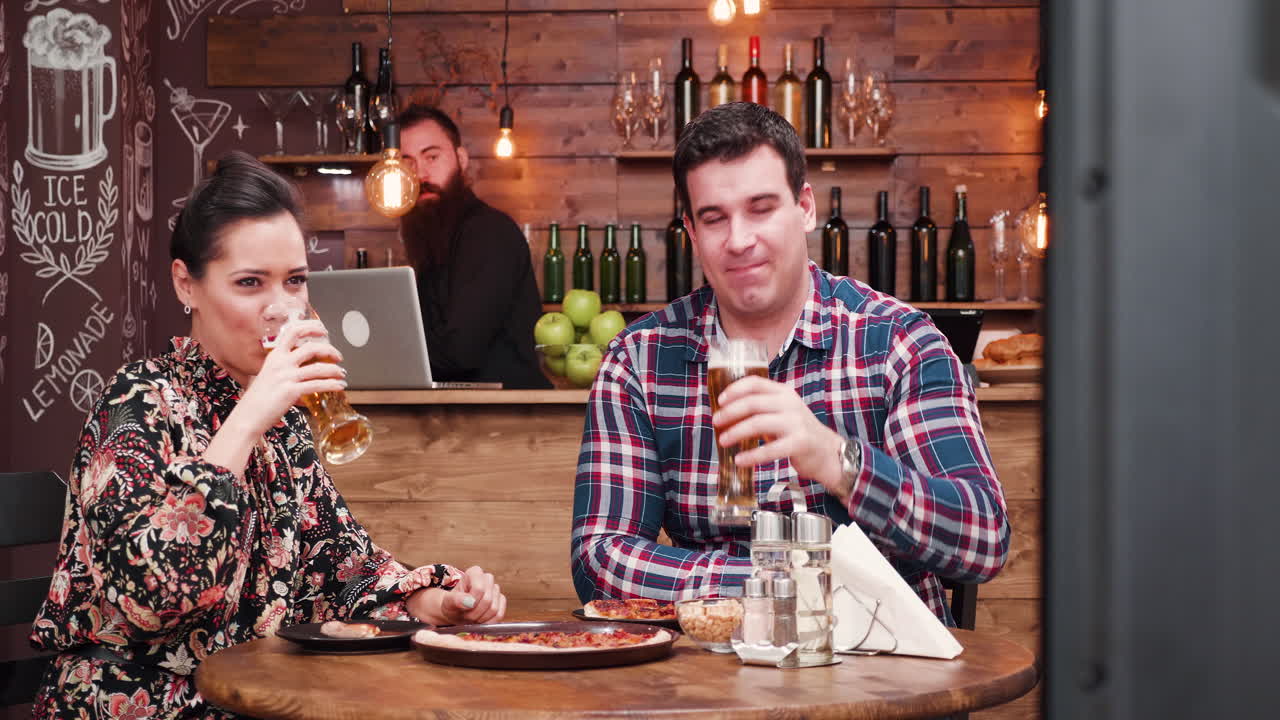 Couple Having Beer and Pizza at a Restaurant