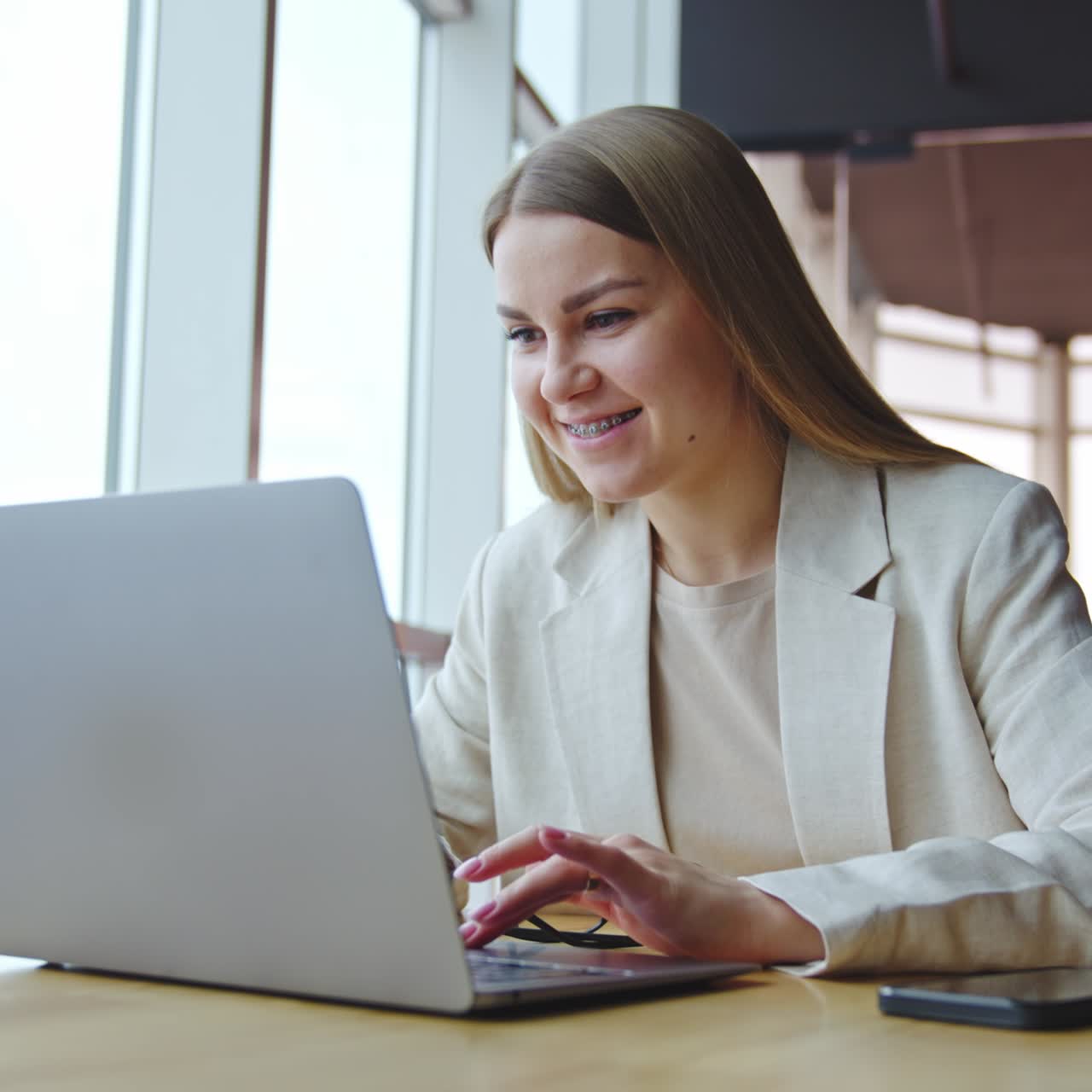 Cheerful young businesswoman working with laptop. Attractive lifestyle girl in modern office