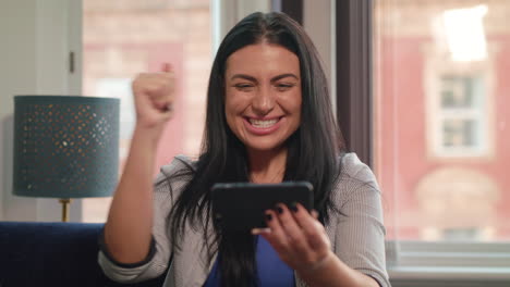una mujer joven y atractiva ve a su equipo ganar un partido y gana una apuesta en línea