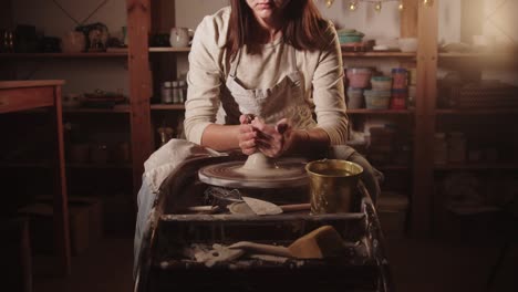 young woman potter wetting her hands and starts forming the clay with her hands