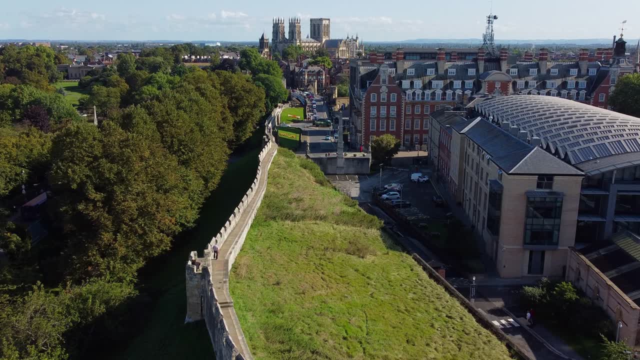 Cinematic drone view of walker along medieval city walls leading to iconic York Minster, England