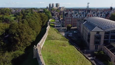 cinematic drone view of walker along medieval city walls leading to iconic york minster, england