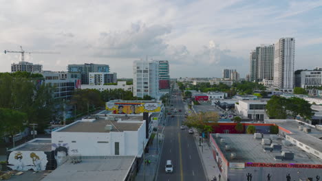 Absteigende-Luftaufnahmen-Der-Stadtentwicklung,-Verschiedene-Niedrige-Gebäude-Entlang-Der-Hauptstraße-Mit-Verkehr.-Miami,-USA