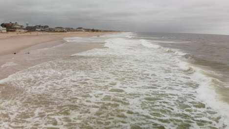 Überflug-Einer-Kleinen-Düne-Aus-Der-Luft-Und-Hinauf,-Um-Die-Strandstadt-Zu-Sehen,-Während-Wellen-An-Die-Küste-Eines-Wunderschönen-Leeren-Strandes-Krachen