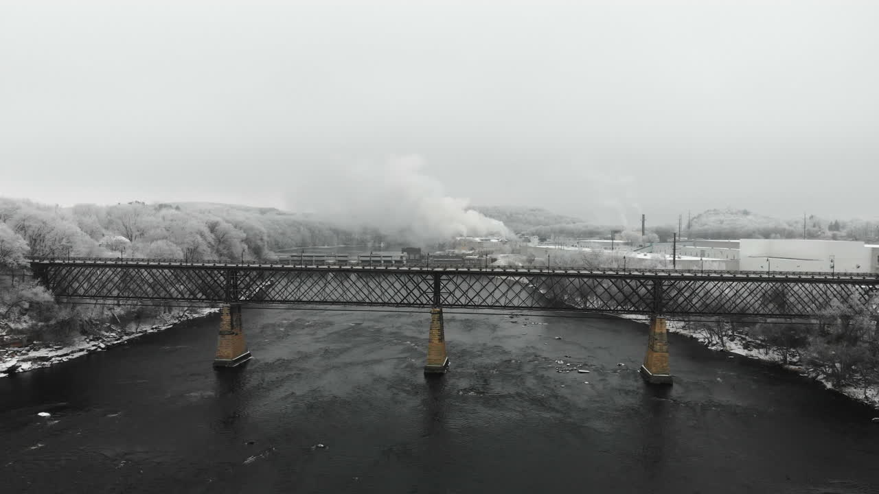 서리가 덮인 나무로 둘러싸인 겨울의 강 다리와 댐