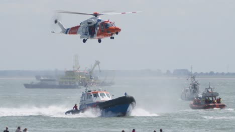 coast guard helicopter hovers over lifeboat for rescue training