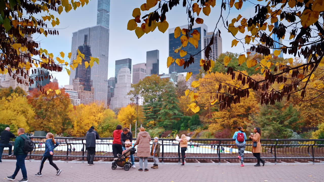 New York, USA, 8 October 2025: Central Park Autumn Scene with Skyline. People enjoying autumn colors in Central Park with Manhattan towers