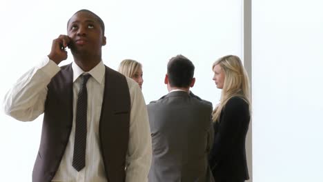 hombre de negocios afroamericano en el teléfono con sus colegas en las imágenes de fondo