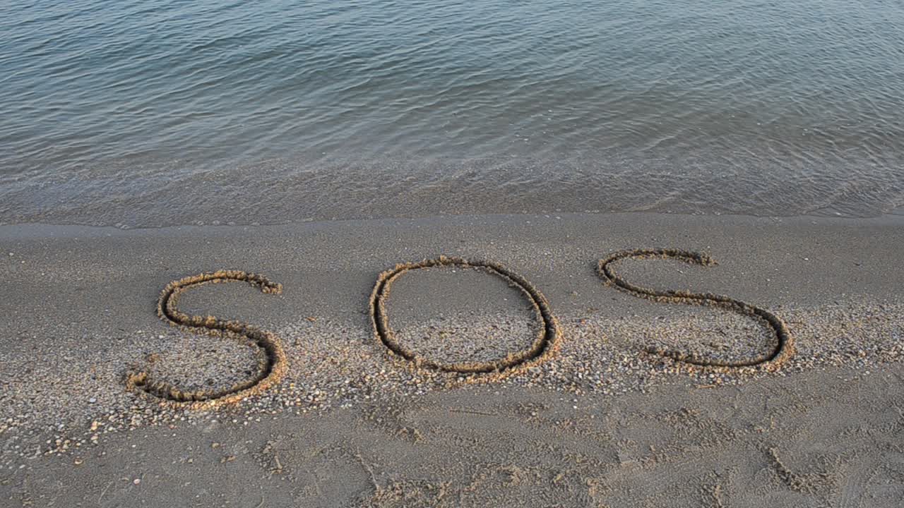The inscription SOS on sand. Shooting on the beach